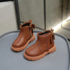 A pair of tan faux leather winter boots for kids, shown from the side on a gray surface.