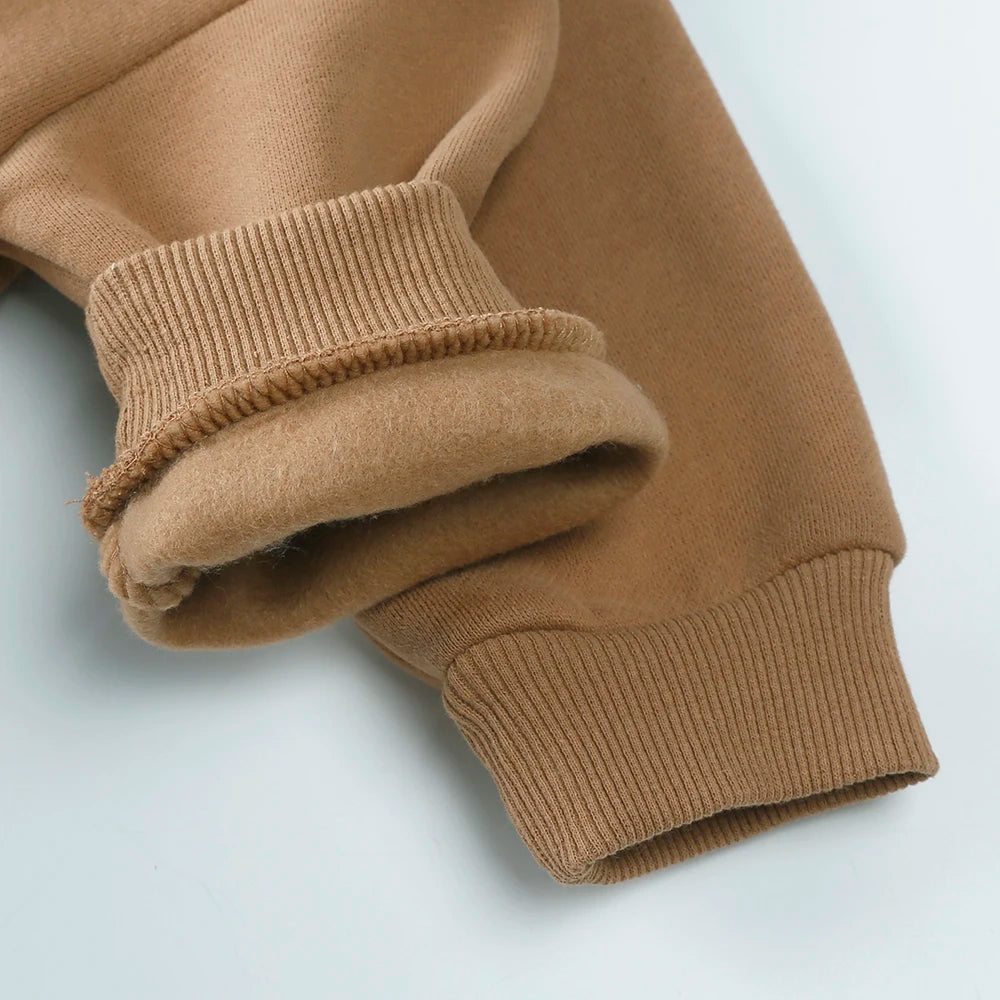A close-up of a tan knitted baby romper for boys and girls, showing the ribbed texture.