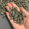 A hand holds a pile of natural crystal chips made of chalcopyrite and pyrite mineral decor.