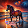 A majestic reddish-brown horse standing in the ocean waves against a vibrant sunset sky.