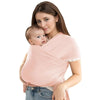 A woman is wearing an ergonomic baby sling carrier while holding a baby.