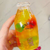 A hand holds a clear bottle filled with colorful fruit-like liquid, serving as a drink cup toy.