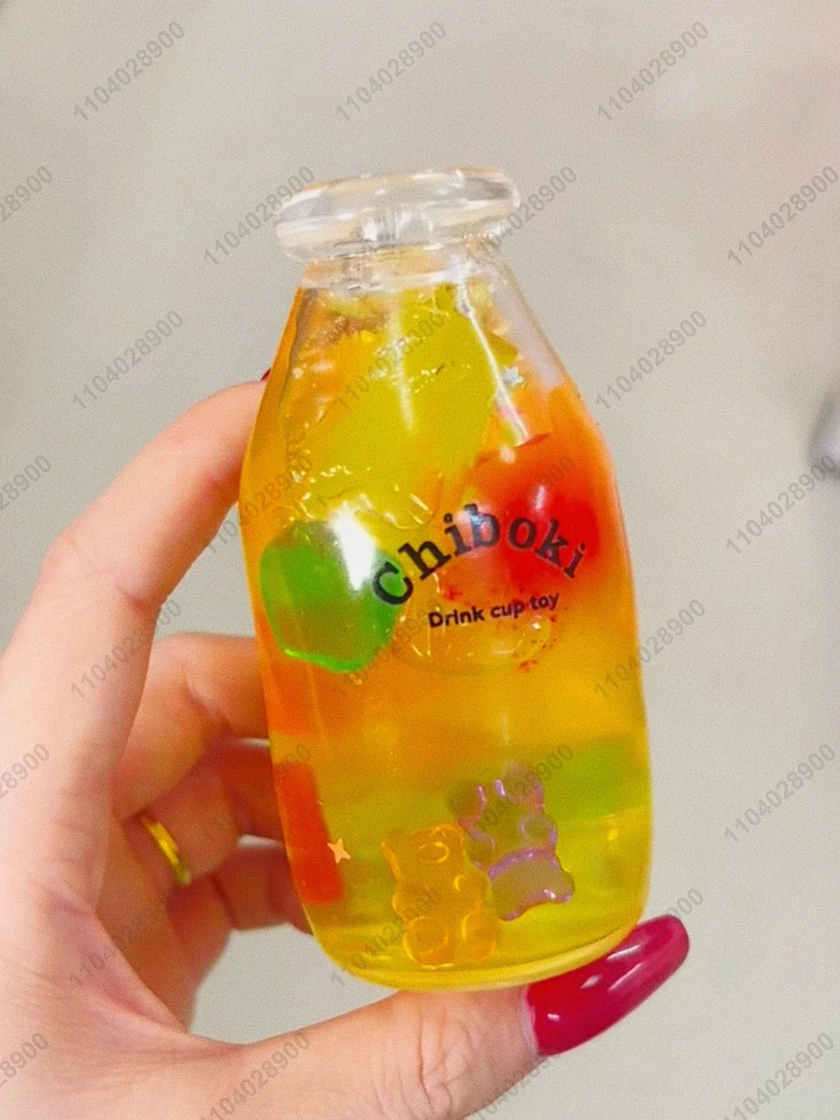 A hand holds a clear bottle filled with colorful fruit-like liquid, serving as a drink cup toy.