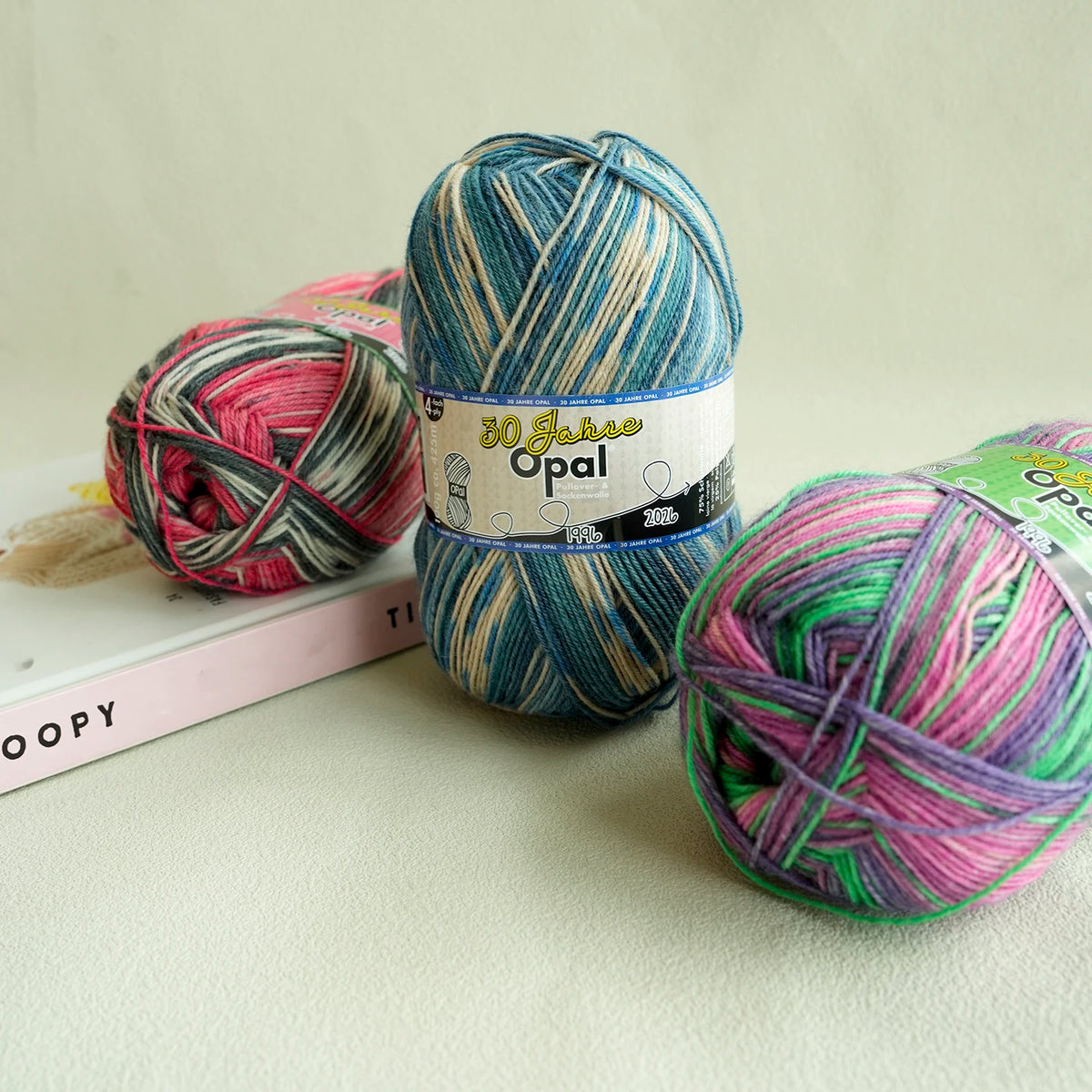 A ball of 30 Jahre Opal 4-ply sock yarn in teal and pink stripes, labeled for knitting or crochet.