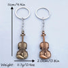 A pair of vintage-style violin keychains made of metal, showing the size and weight.