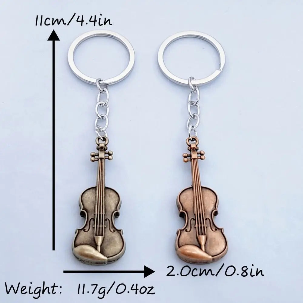 A pair of vintage-style violin keychains made of metal, showing the size and weight.