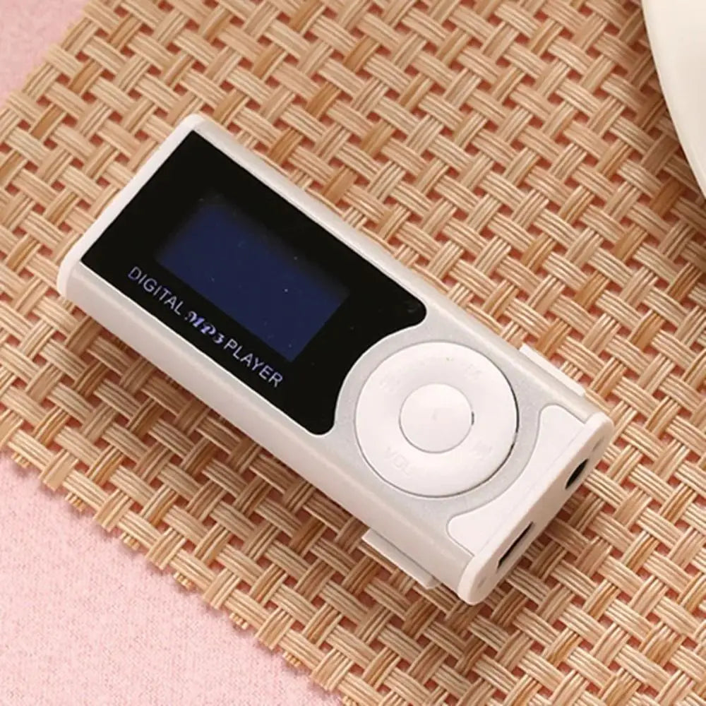 Ein weißer tragbarer MP3-Player mit schwarzem LCD-Display liegt auf einer gewebten Matte.
