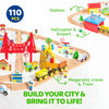 A wooden train set featuring various vehicles, including a helicopter and a magnetic crane, built into a city scene.