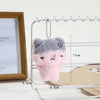 A fluffy pink and gray plush cat keychain hanging on a white wire rack.
