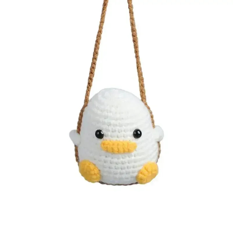 Handmade crochet chicken charm with yellow feet and white body hanging from a brown string.