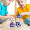Two toddlers interact with purple and blue octopus squishy stress balls on a light-colored carpet.