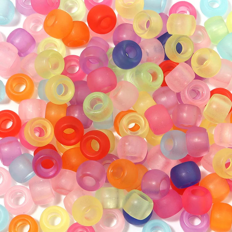 A large pile of colorful rainbow pony beads in various shades including pink, orange, yellow, and blue.