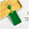 A green retractable ID badge holder with a clip and keychain is placed on a light wooden tray.