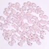 A pile of small, faceted pink crystal bicone glass beads for jewelry making.