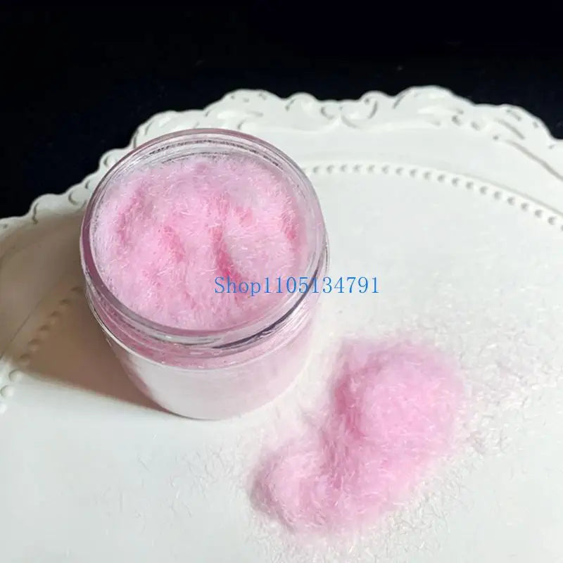 A small glass jar of pink adhesive flocking powder with loose powder spilled on a white surface.