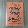 A brown leather-bound Bible Study Guide book with embossed text and a cross symbol.
