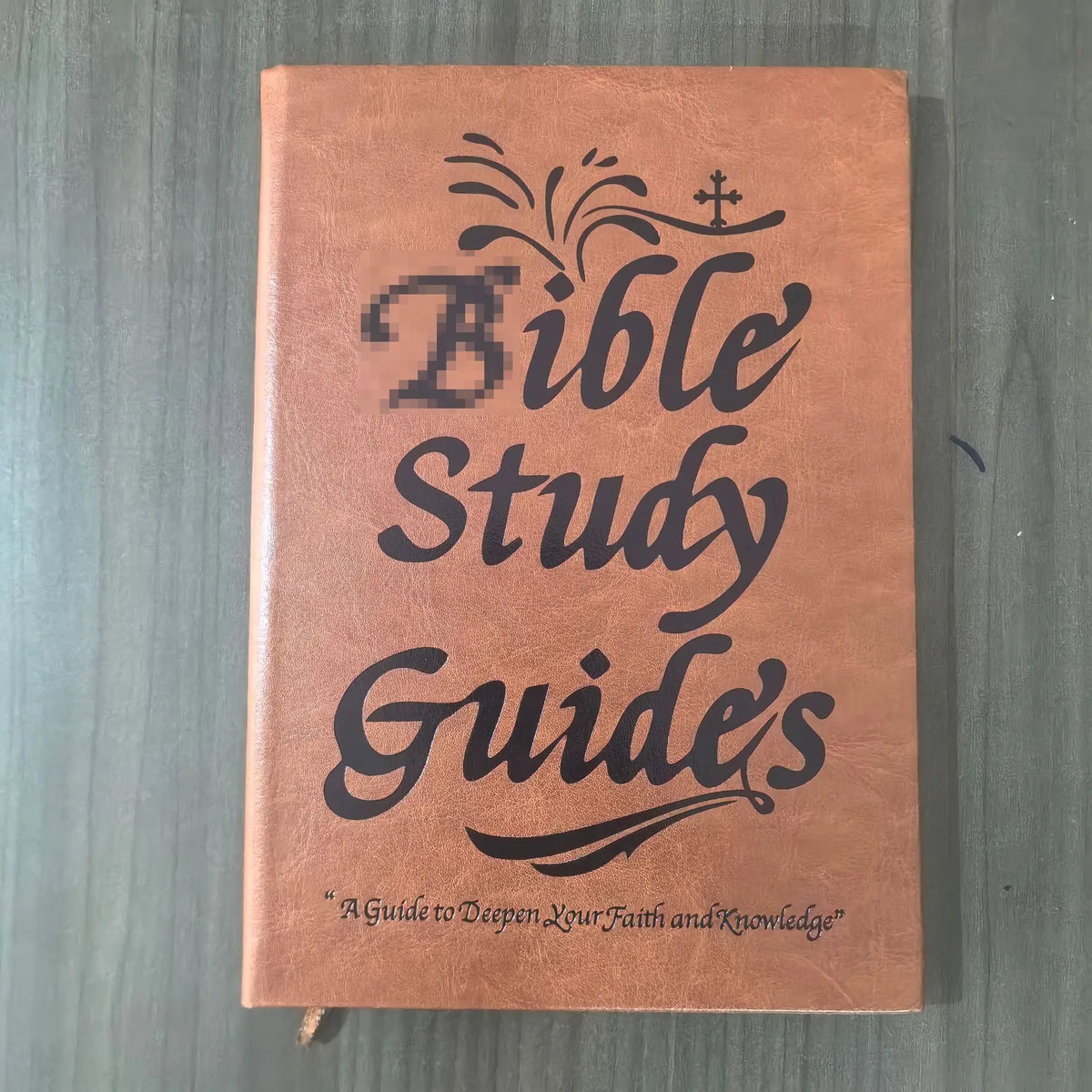 A brown leather-bound Bible Study Guide book with embossed text and a cross symbol.