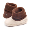 A pair of brown knit baby winter snow boots with fuzzy ball accents shown from the side.