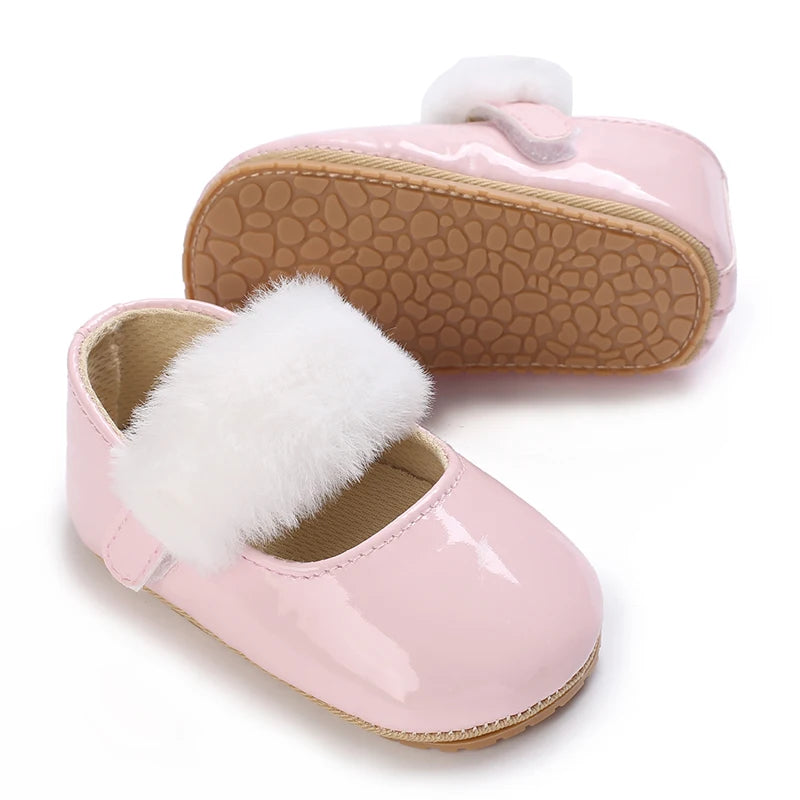 Pink lace-trimmed moccasin shoes for a baby girl with white faux fur trim