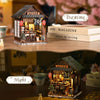A miniature Japanese izakaya dollhouse kit with LED lighting displayed next to a daytime and night sign.