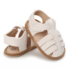 A pair of beige and white breathable baby first walker sandals with soft anti-slip soles.