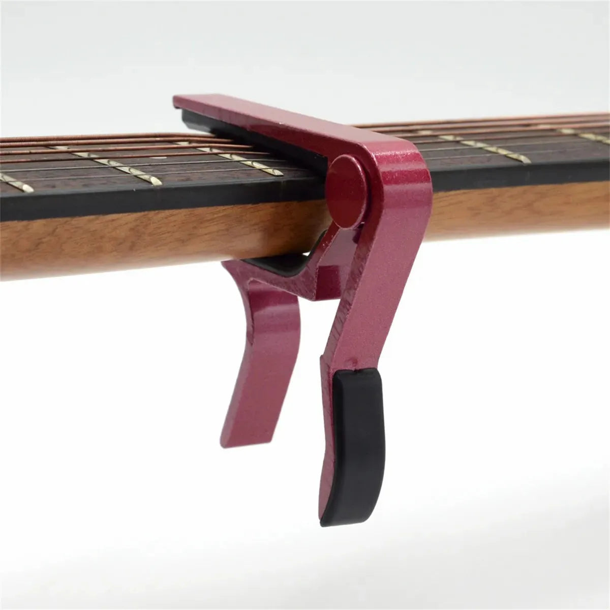 A close-up of a red aluminum alloy quick-change guitar capo mechanism attached to a wooden guitar neck.