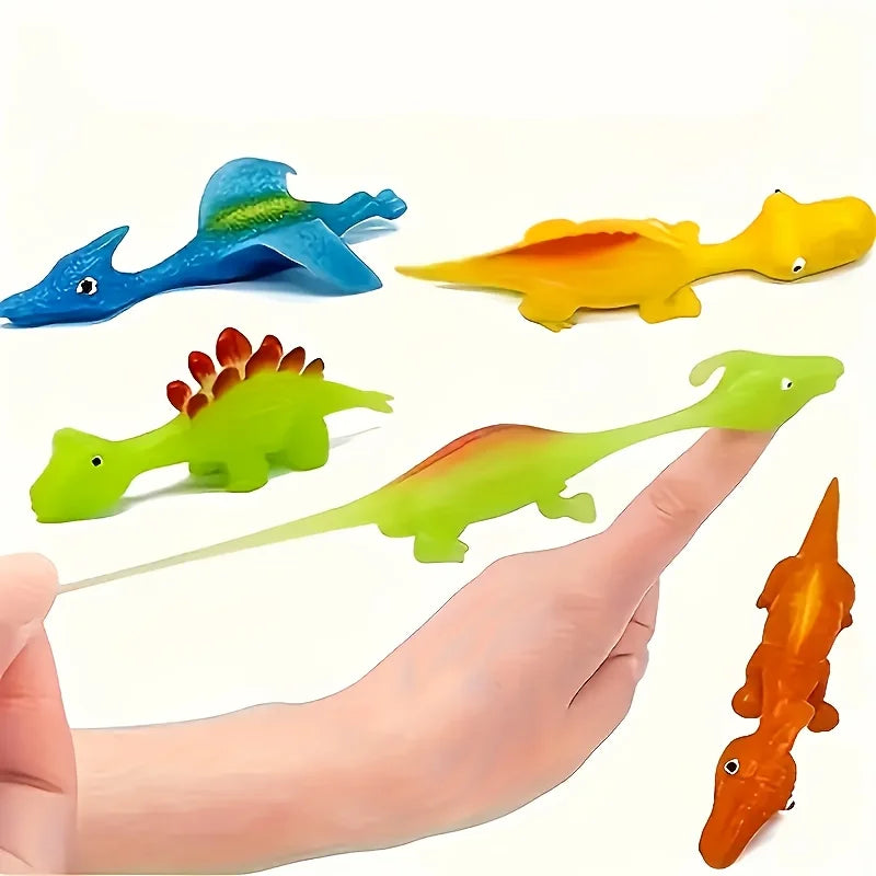 A hand holds several colorful mini dinosaur finger slingshots, including blue, yellow, green, and orange dinosaurs.