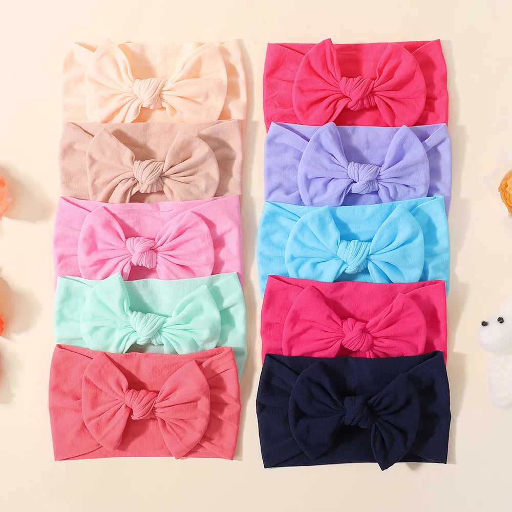 A collection of pink, purple, and blue nylon knit bow headbands for baby girls.
