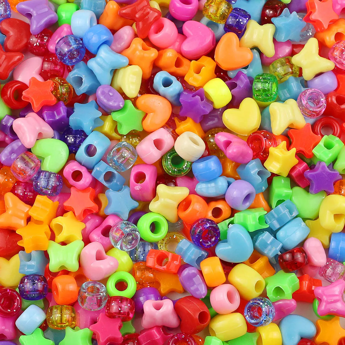 A close-up of a large pile of colorful pony beads in various shapes and colors for jewelry making and crafts.