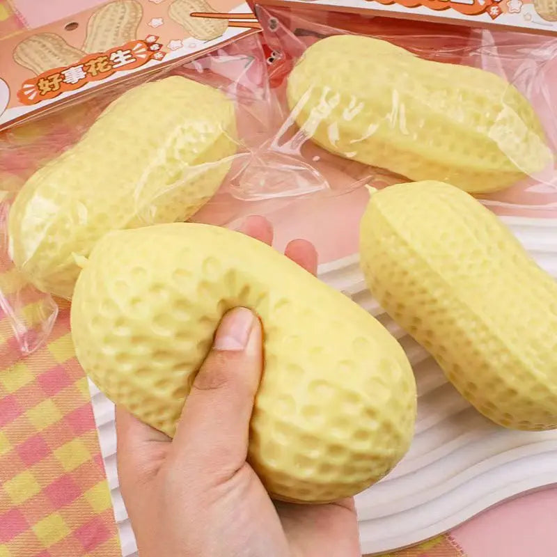 A hand is squeezing a yellow strawberry-shaped fidget toy packaged in plastic.
