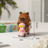 A small, brown capybara-themed building block figure with pink accents and a light pink cart, shown against a white backgroun
