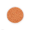 A clear plastic container filled with small, round, light orange glass seed beads for jewelry making.