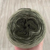 A ball of gray and white rainbow gradient mercerized cotton cake yarn is held in a hand.