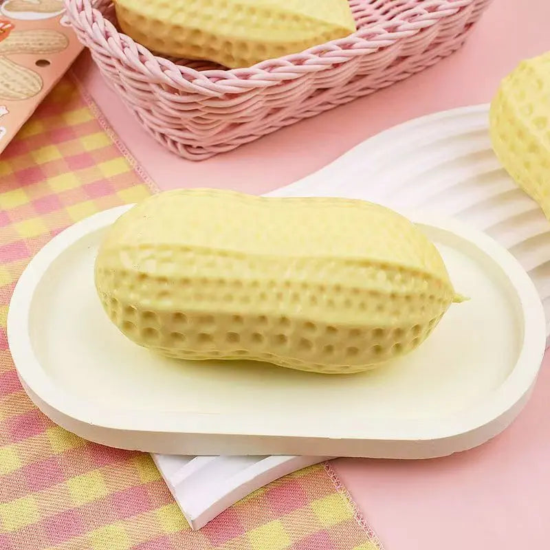 A yellow squishy stress ball shaped like a peanut is displayed on a white plate with pink and yellow checkered fabric.