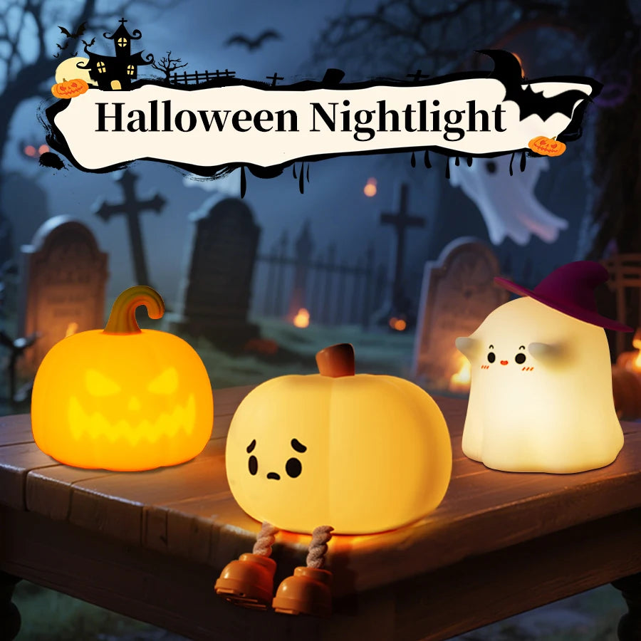 A glowing yellow pumpkin LED night light with a carved face sits on a wooden surface in a Halloween themed outdoor setting.