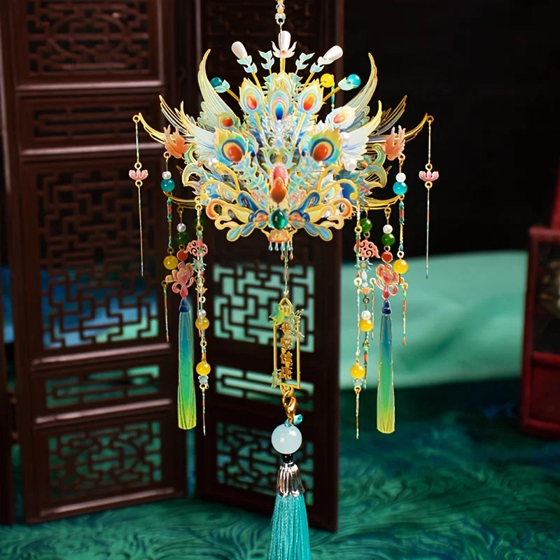 A detailed 3D metal phoenix crown model kit with colorful feathers and jewels displayed in front of a dark wooden screen.