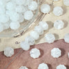 A collection of translucent white gold-traced pumpkin resin beads for jewelry making scattered on a light surface.