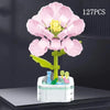 A set of 127 plastic rose flower building blocks in various shades of pink and yellow arranged on a white base.