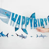 A blue geometric shark banner spelling out Happy Birthday against a white background.