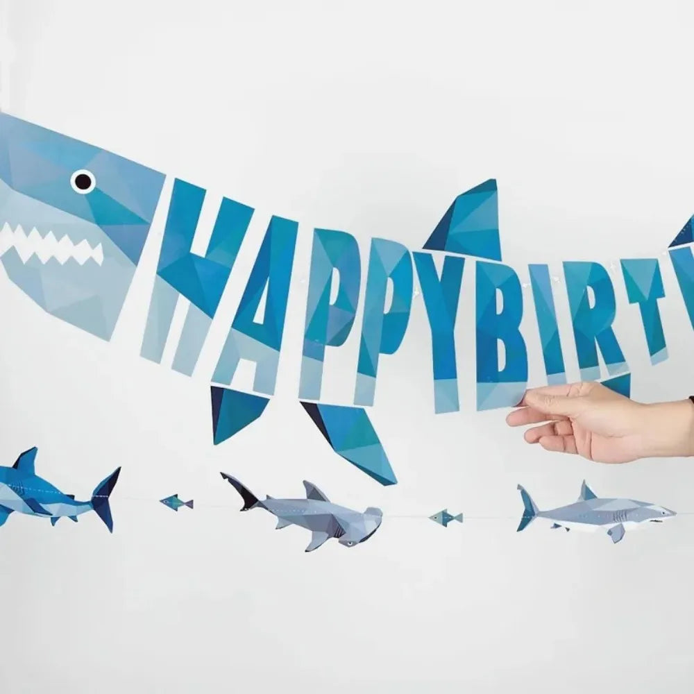 A blue geometric shark banner spelling out Happy Birthday against a white background.