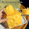 A hand holds a large yellow cheese-shaped squishy fidget toy on a white plate.
