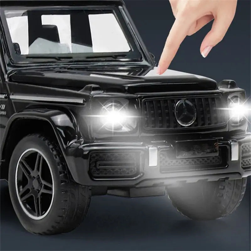 A hand points at a black diecast metal RV camper truck model with lights and sound.