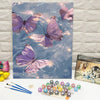 A painting of purple and pink butterflies on canvas next to a butterfly paint by numbers kit.