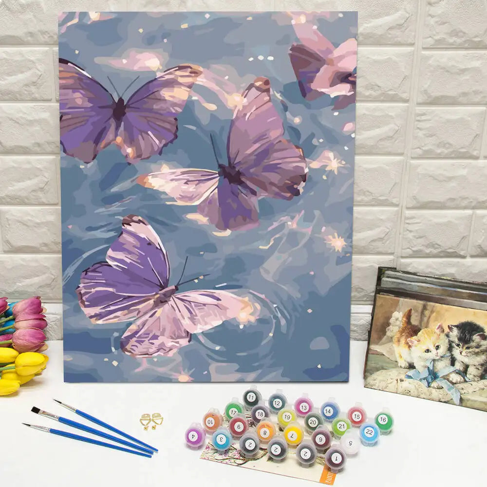 A painting of purple and pink butterflies on canvas next to a butterfly paint by numbers kit.