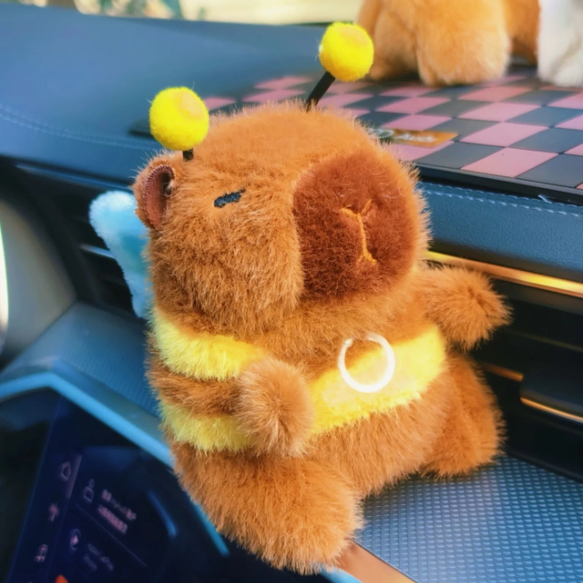 An orange capybara plush toy with yellow accents sitting on a dark surface.