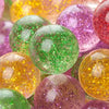 A close-up of various colorful glitter bouncy balls in shades of green, yellow, and purple.