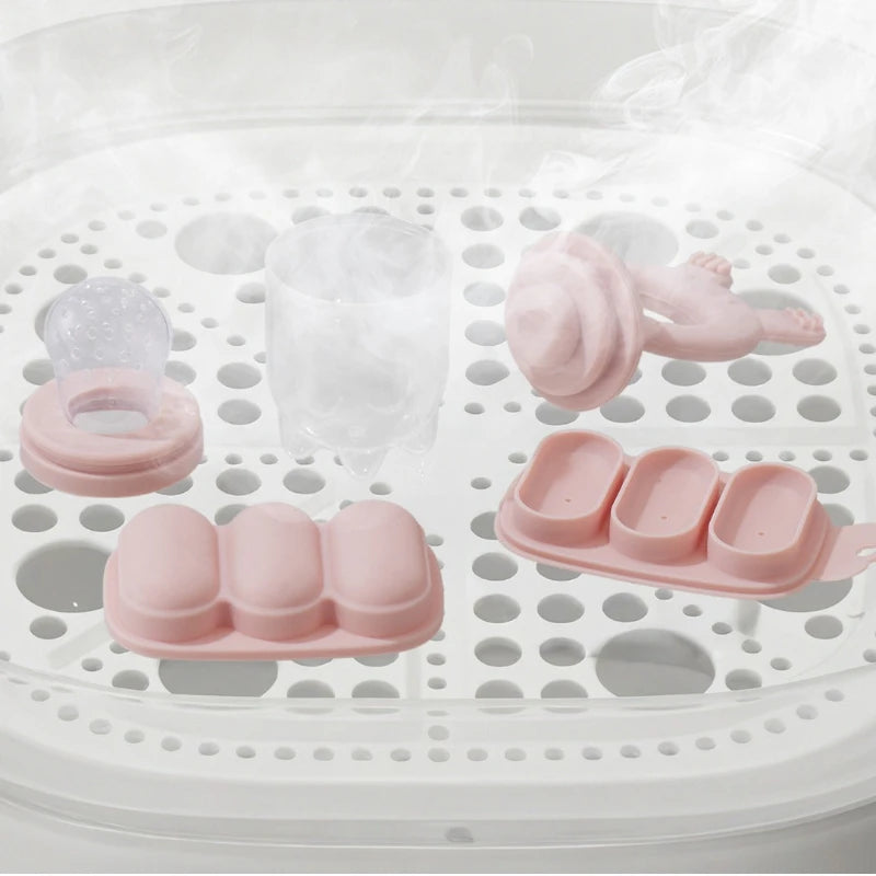 A silicone fruit food feeder and cooling mold set with various pink silicone shapes placed on a white grid tray.