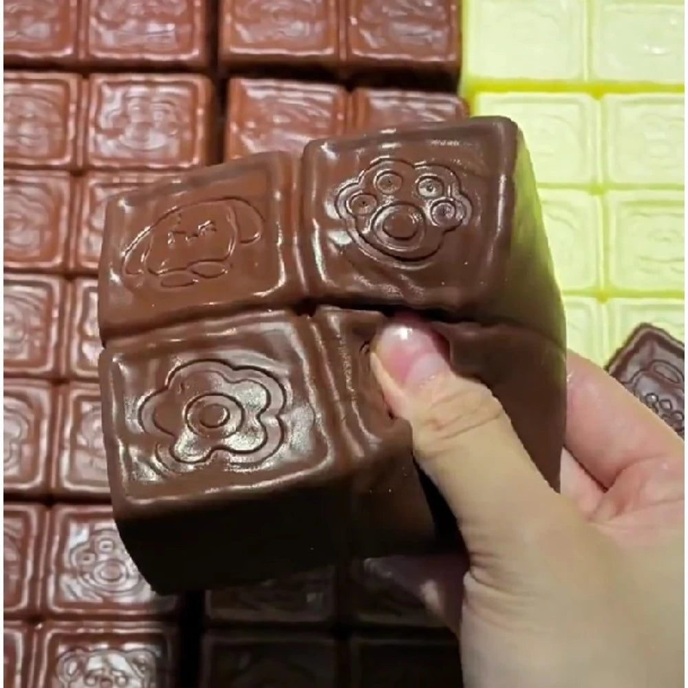 A hand holds a brown squishy toy shaped like a strawberry with embossed details against a background of similar toys.