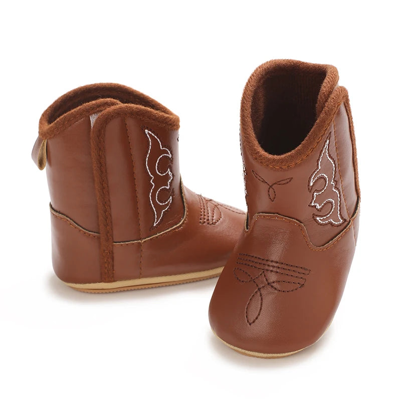 A pair of brown baby western booties with suede material and a soft non-slip sole.