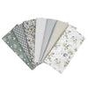 A collection of seven patterned cotton fabric squares for quilting and patchwork.